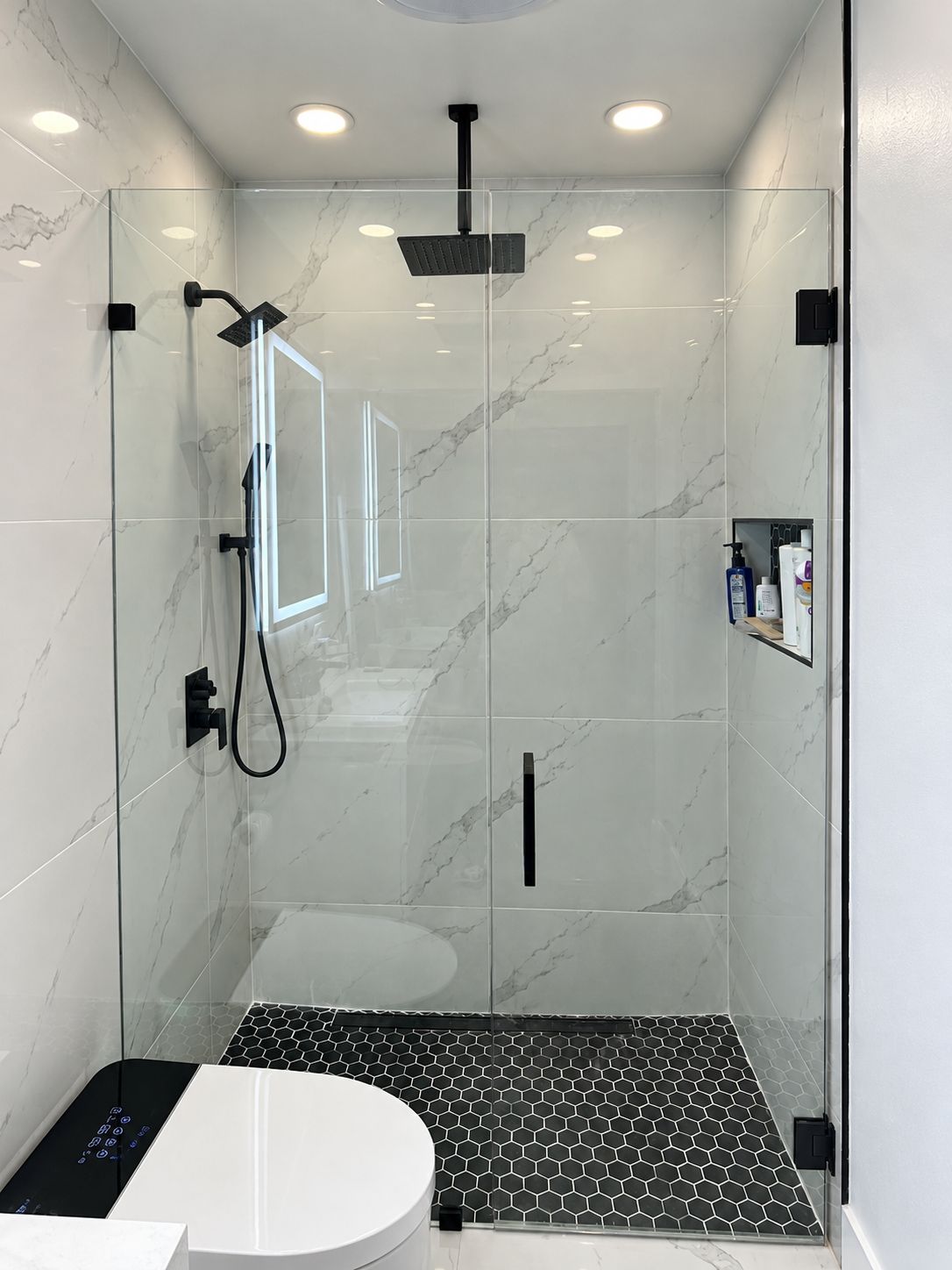 Glass shower with black hexagon tile floor and marble walls, bathroom remodel by MySFContractor