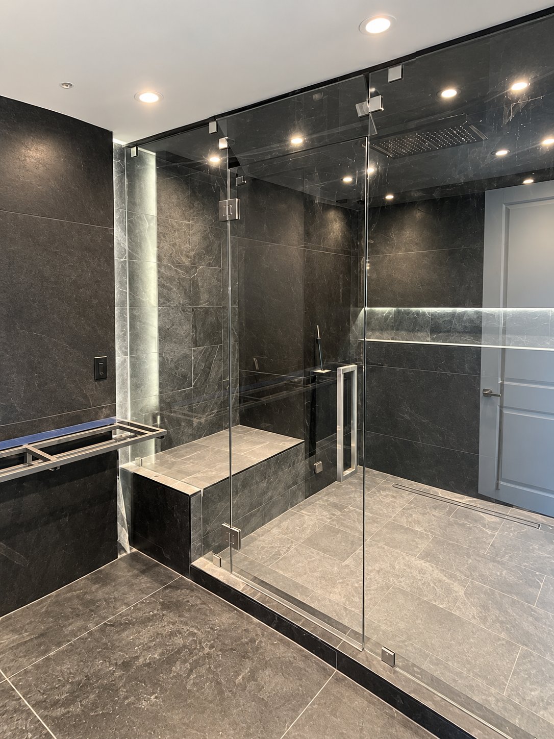Walk-in glass steam shower with dark stone tile, built-in bench and LED lighting, bathroom remodel by MySFContractor