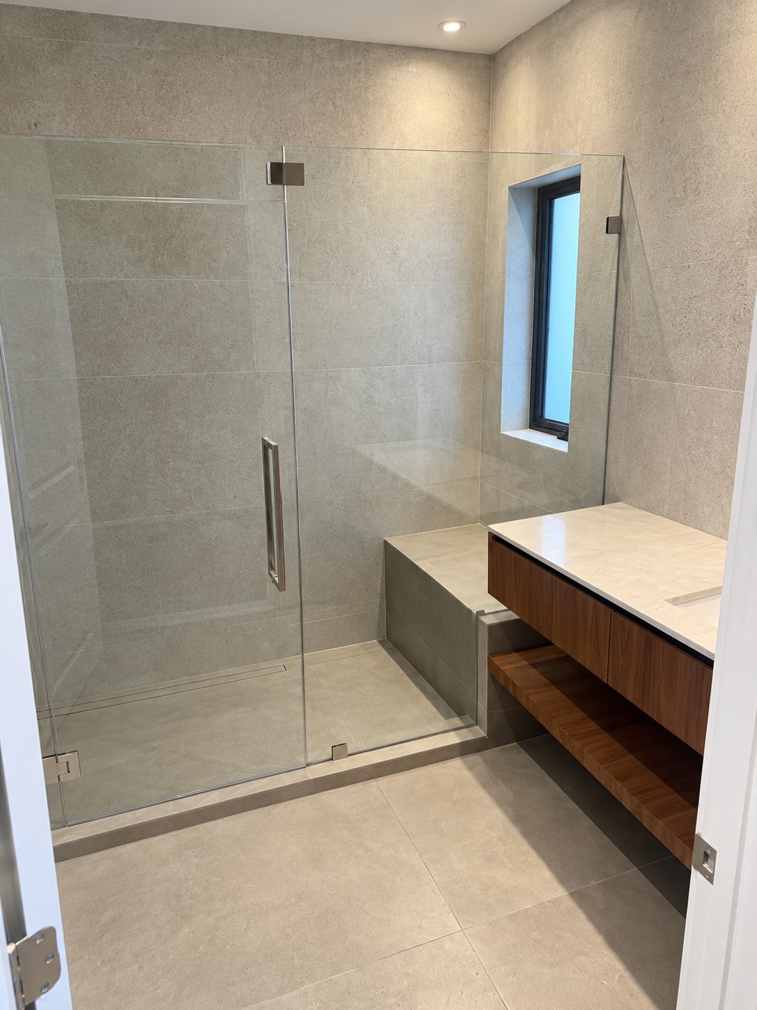 Frameless glass shower with tiled bench and floating walnut vanity, bathroom remodel by MySFContractor