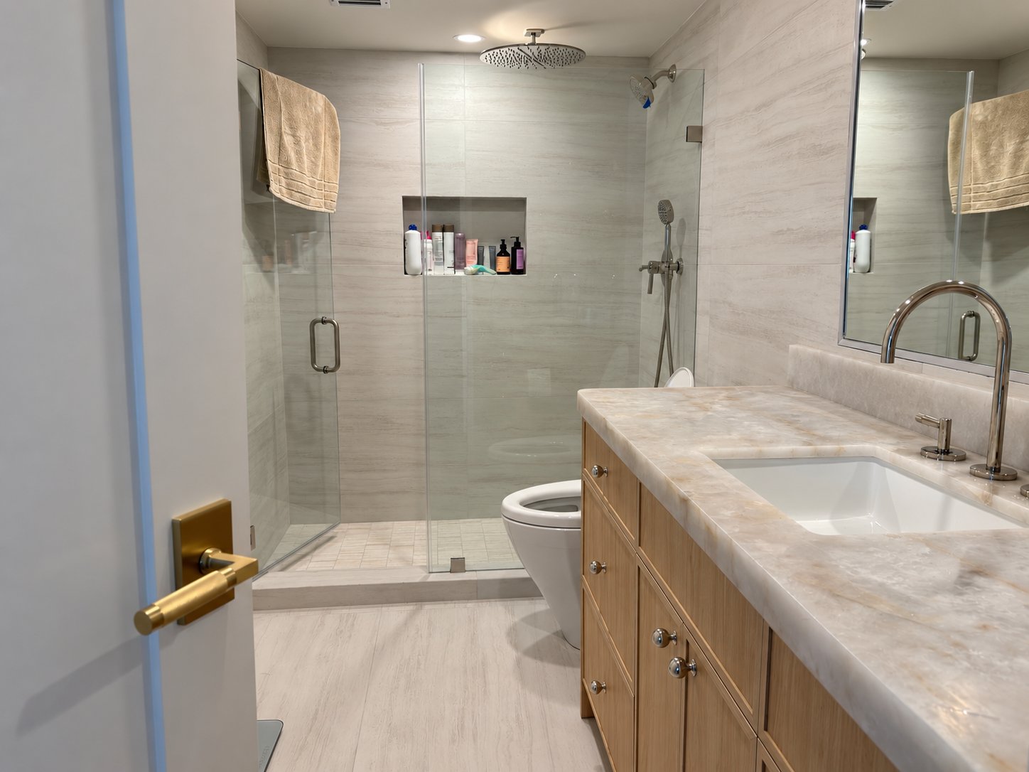 Remodeled bathroom with stone-look tile, glass shower enclosure and oak vanity with polished nickel faucet by MySFContractor